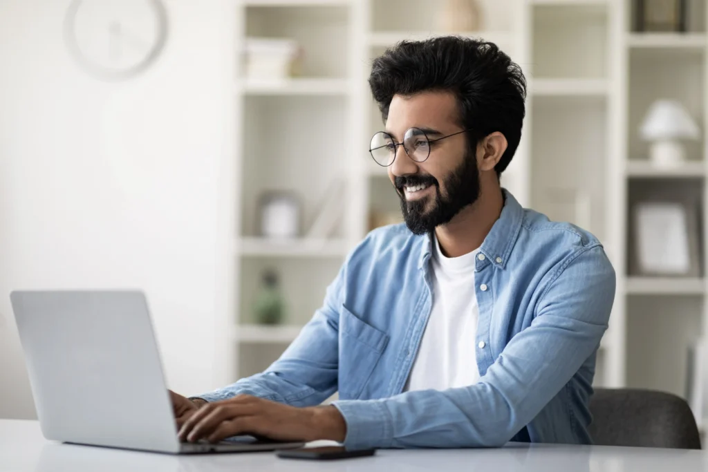 handsome indian male freelancer using laptop computer while working home office